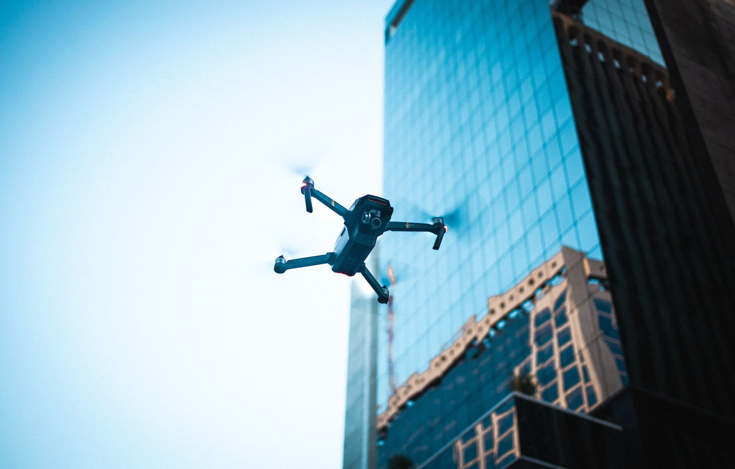 A drone flying beside the glass facade of a tall office building