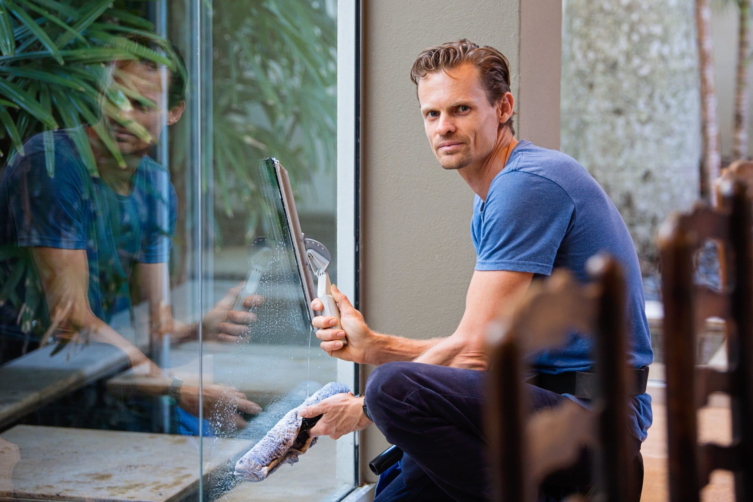 A window cleaner drawing a squeegee across a large pane of glass