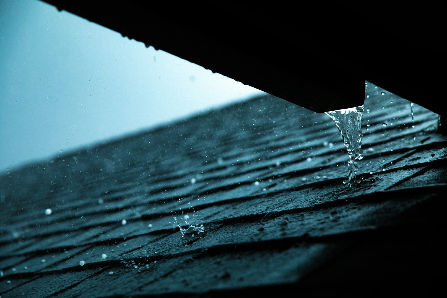 Water overflowing from a blocked gutter during rain.