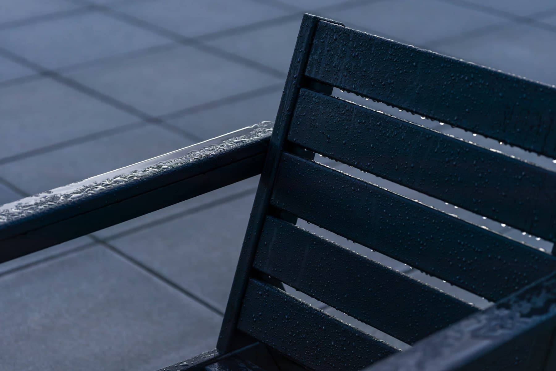 A patio and garden bench in the rain.